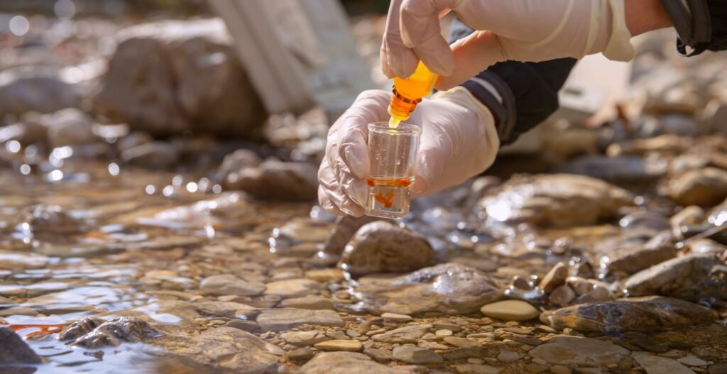 Female biologist adding reagent into a vial with water sample