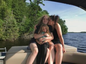 Candid moment of mom and daughters laughing together on back of pontoon boat.